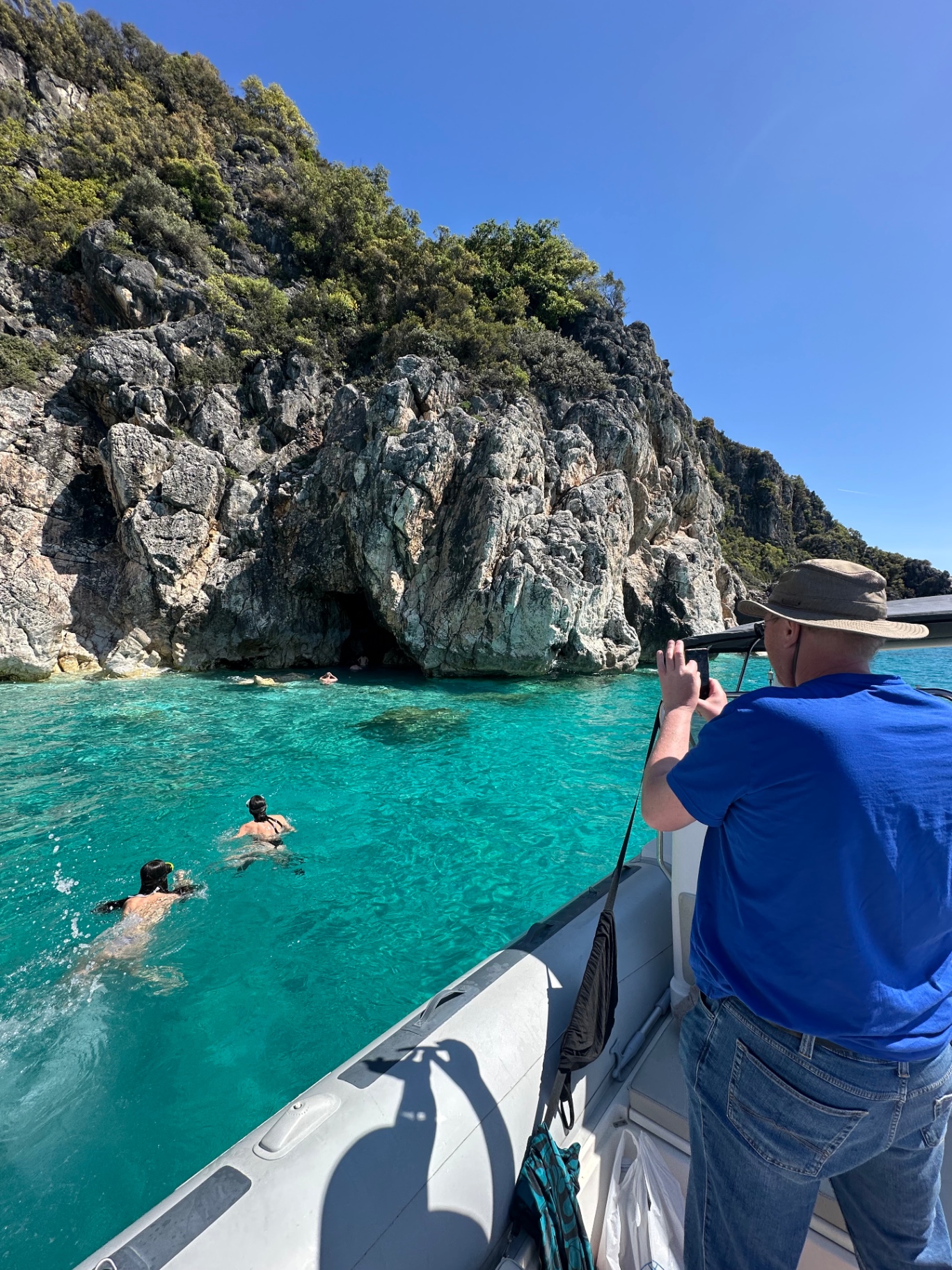 Snorkeling in turquoise water by a cliff cave